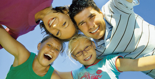 A family in a huddle all smiling and looking down at the camera